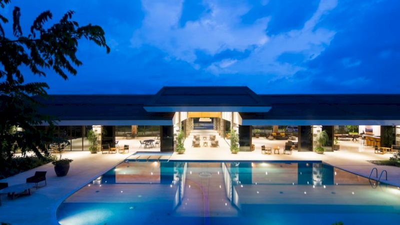 A pool area at night with a large building in the background