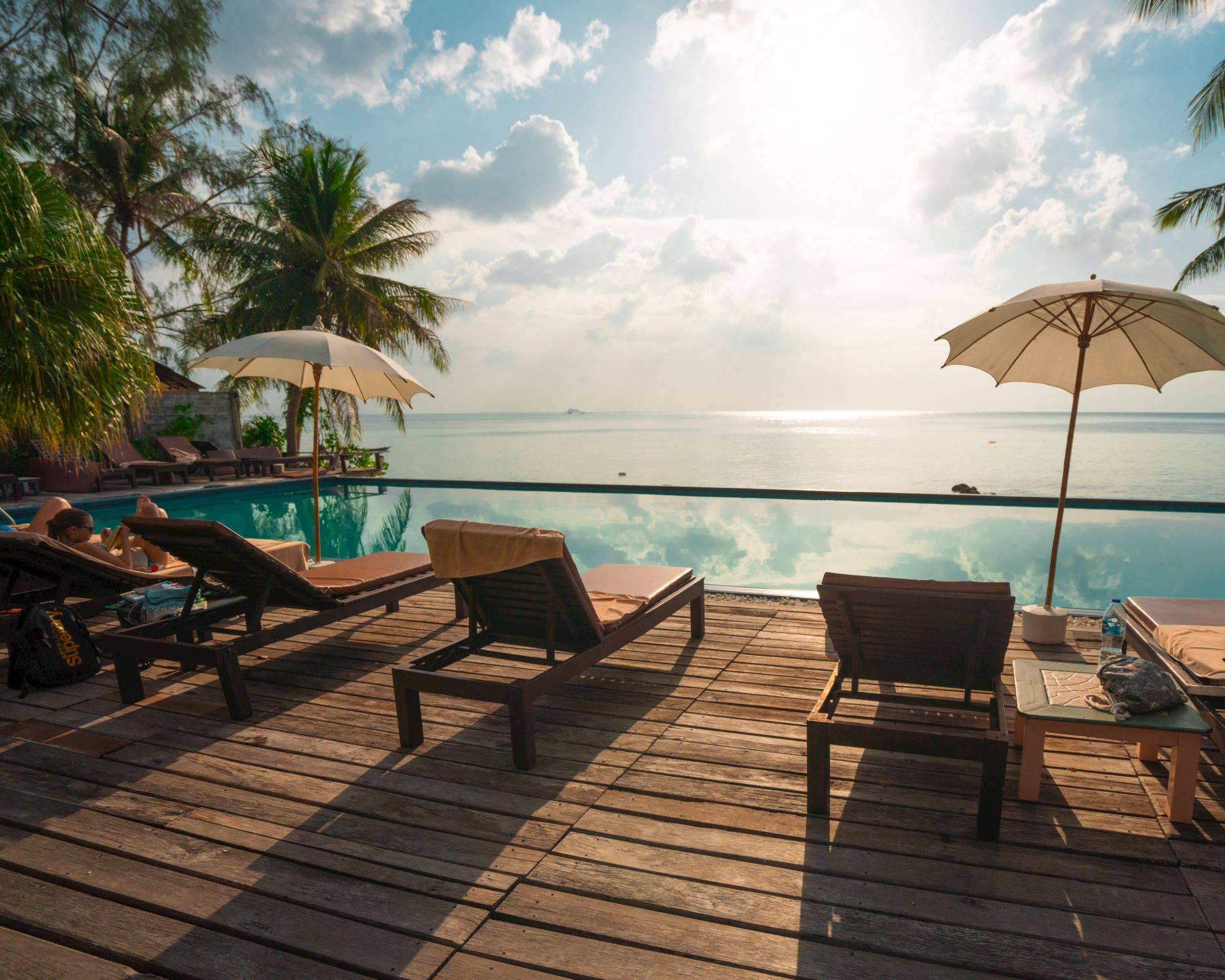 A serene beachside setting with lounge chairs, umbrellas, and a calm sea view under a bright sky.
